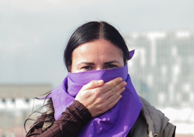 Latin woman victim in purple with hand as a sign of silence to raise awareness