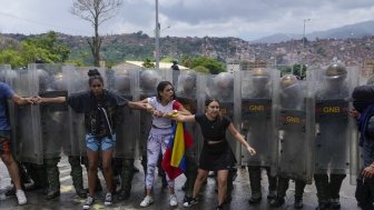 Residents try to block a street to protest the official results the day after the presidential election as National Guards work to remove them in Caracas, Venezuela, Monday, July 29, 2024. (AP Photo/Fernando Vergara)