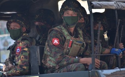 Soldiers in uniforms and masks sitting on a truck.