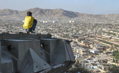 KABUL, AFGHANISTAN 2012: Boy sitting on Destroyed Tank on the hills over Kabul City in Afghanistan