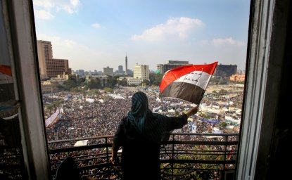 Cairo, Egypt - 2013: A woman wearing a headscarf is waving the Egyptian flag against Tahriri Square. After the military coup of General Sisi, supporters of President Morsi resist in Adeviye Square.