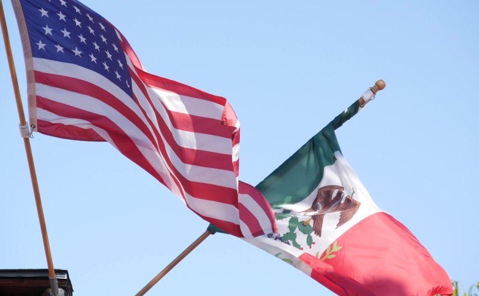 Mexican tricolor and American flag waving on wind.