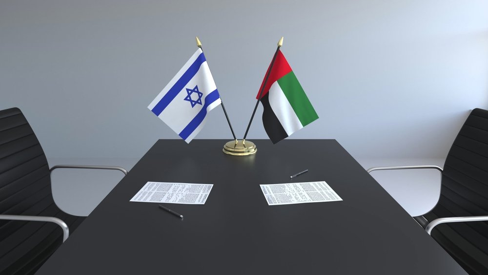 The flags of Israel and the UAE on a conference room table.