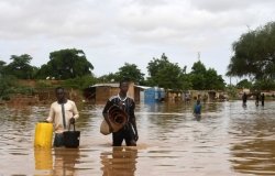 In the Kirkissoye neighborhood in Niamey, people carry their belongings while walking in a street flooded by waters from the Niger river. 