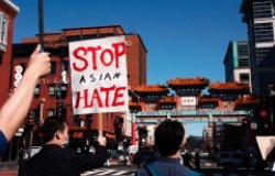 People march in the streets of Chinatown, one holding a sign that reads Stop Asian Hate