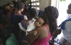 A woman waits for her baby's check-up at a school that serves as a shelter for people displaced by gang violence in Port-au-Prince, Haiti, Friday, Aug. 23, 2024. (AP Photo/Odelyn Joseph)