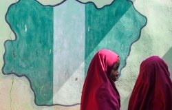 Girl students pass a classroom with the map and flag of Nigeria painted on it, at Success Private School, one of the first schools attacked by Boko Haram in '09.