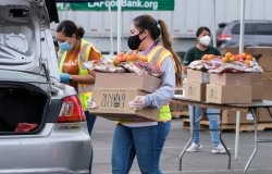 A volunteer loads food into the trunk of a vehicle during a drive-thru food distribution by the Los Angeles Regional Food Bank in Glendora, California